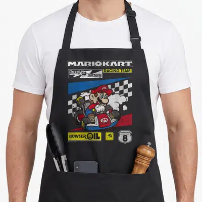 Drifting racing apron - Mario driving a red kart with MARIOKART and BOWSER OIL sponsor logos on a checkered background — shown on a black cotton canvas apron against a white background
