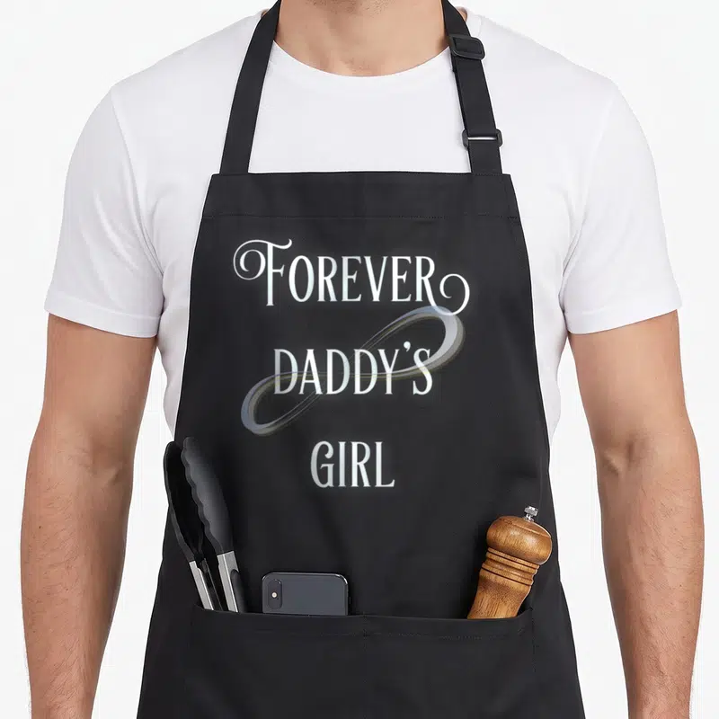 Forever daddy apron - Stacked white text FOREVER DADDY'S GIRL with light blue infinity symbol overlay — shown on a black cotton canvas apron against a white background