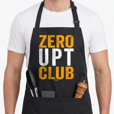 Upt zero apron - Stacked orange and white text reading ZERO UPT CLUB on a dark background — shown on a black cotton canvas apron against a white background