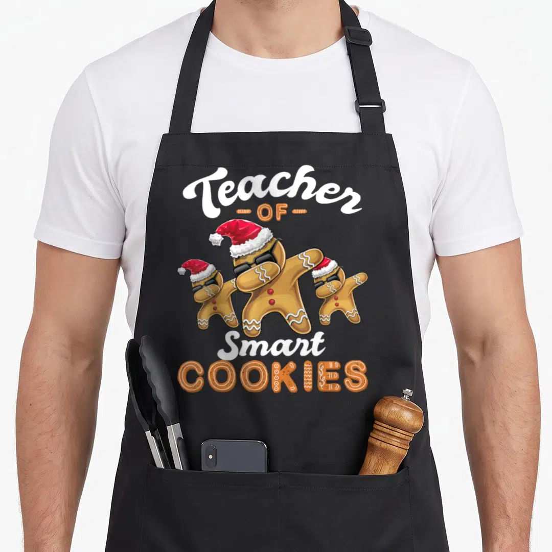 Dabbing smart apron - Three dabbing gingerbread men in Santa hats and sunglasses with Teacher of Smart Cookies text — shown on a black cotton canvas apron against a white background