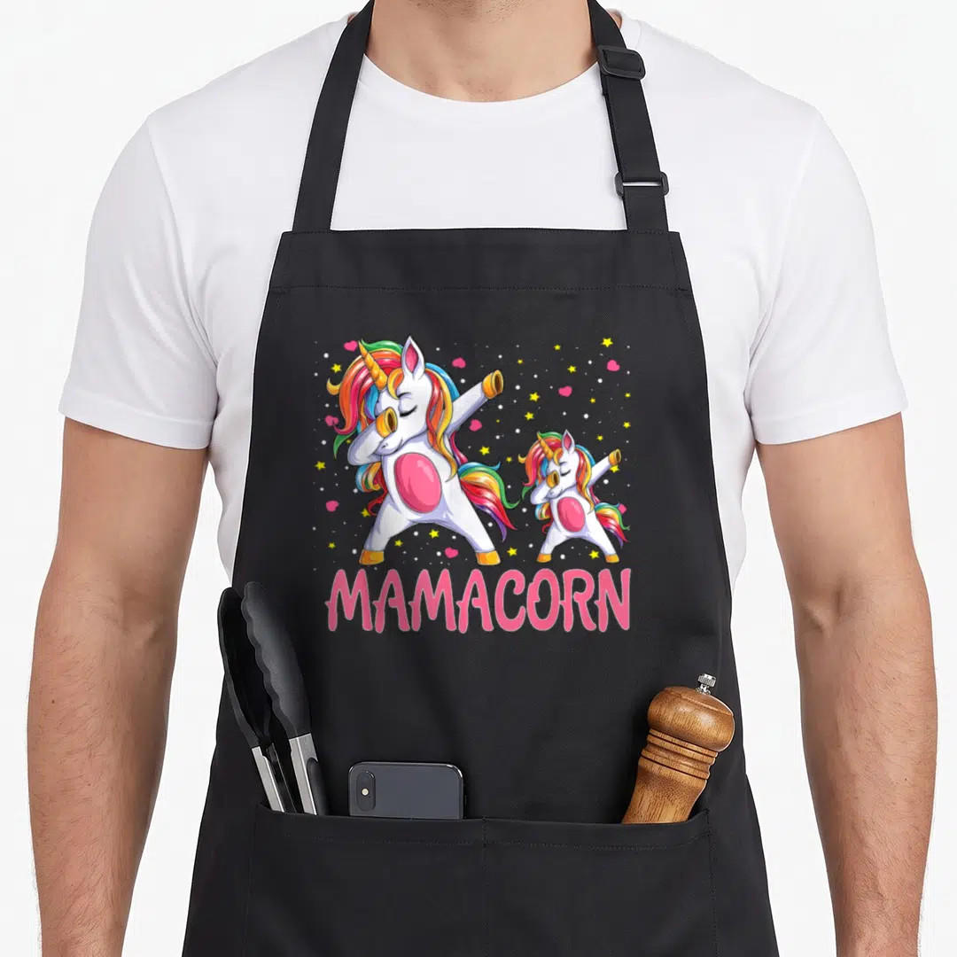 Mamacorn mother's day aprons - Two white unicorns dabbing with rainbow manes and pink MAMACORN text below — shown on a black cotton canvas apron against a white background
