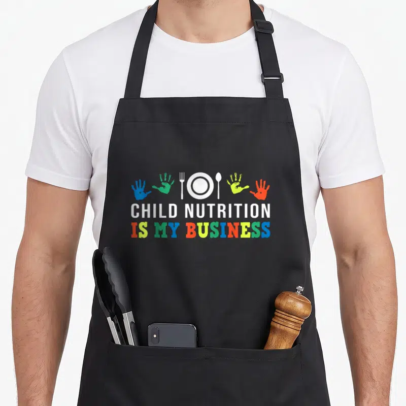 Lunch nutrition cafeteria aprons - Colorful handprints and white cutlery above stacked text reading Child Nutrition Is — shown on a black cotton canvas apron against a white background