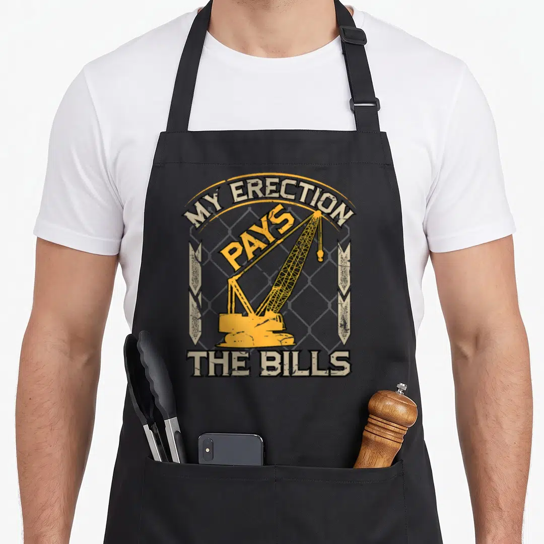 Crane construction apron - Yellow crane over grey grid with MY ERECTION PAYS THE BILLS text in distressed style — shown on a black cotton canvas apron against a white background
