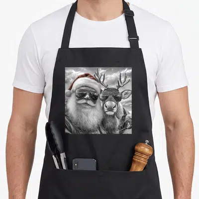 Reindeer santa claus apron - Santa and reindeer photo wearing aviator sunglasses, red hat, leather jacket, grey white — shown on a black cotton canvas apron against a white background
