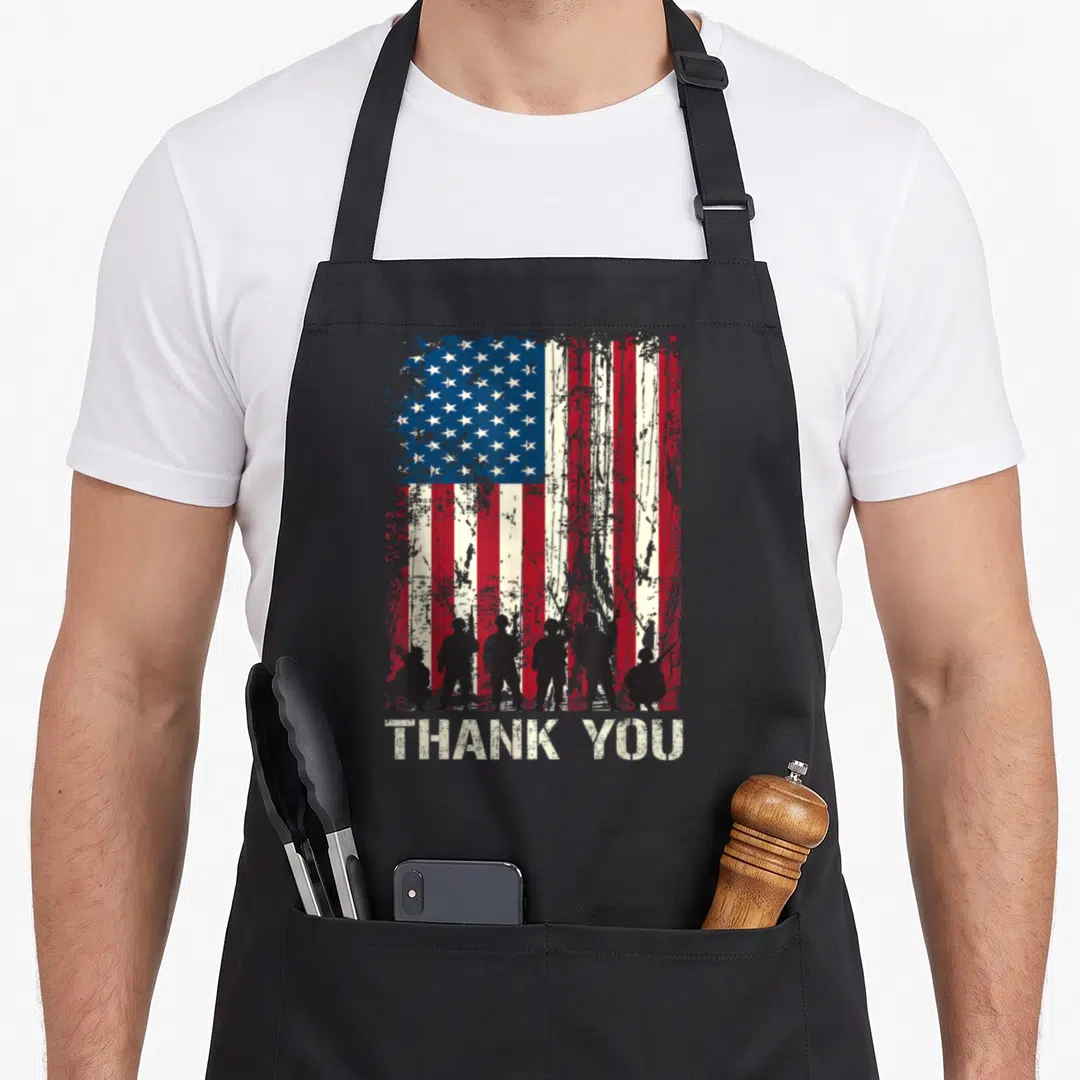 Veteran patriotic american flag apron - Soldier silhouettes against distressed US flag with THANK YOU text below — shown on a black cotton canvas apron against a white background