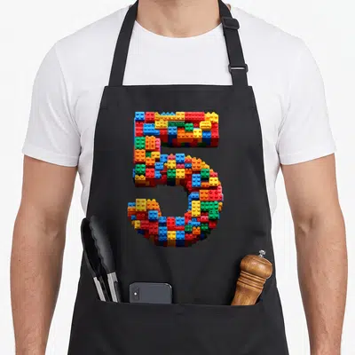 Block master building aprons - Number 5 formed by red blue yellow green and orange interlocking plastic bricks — shown on a black cotton canvas apron against a white background