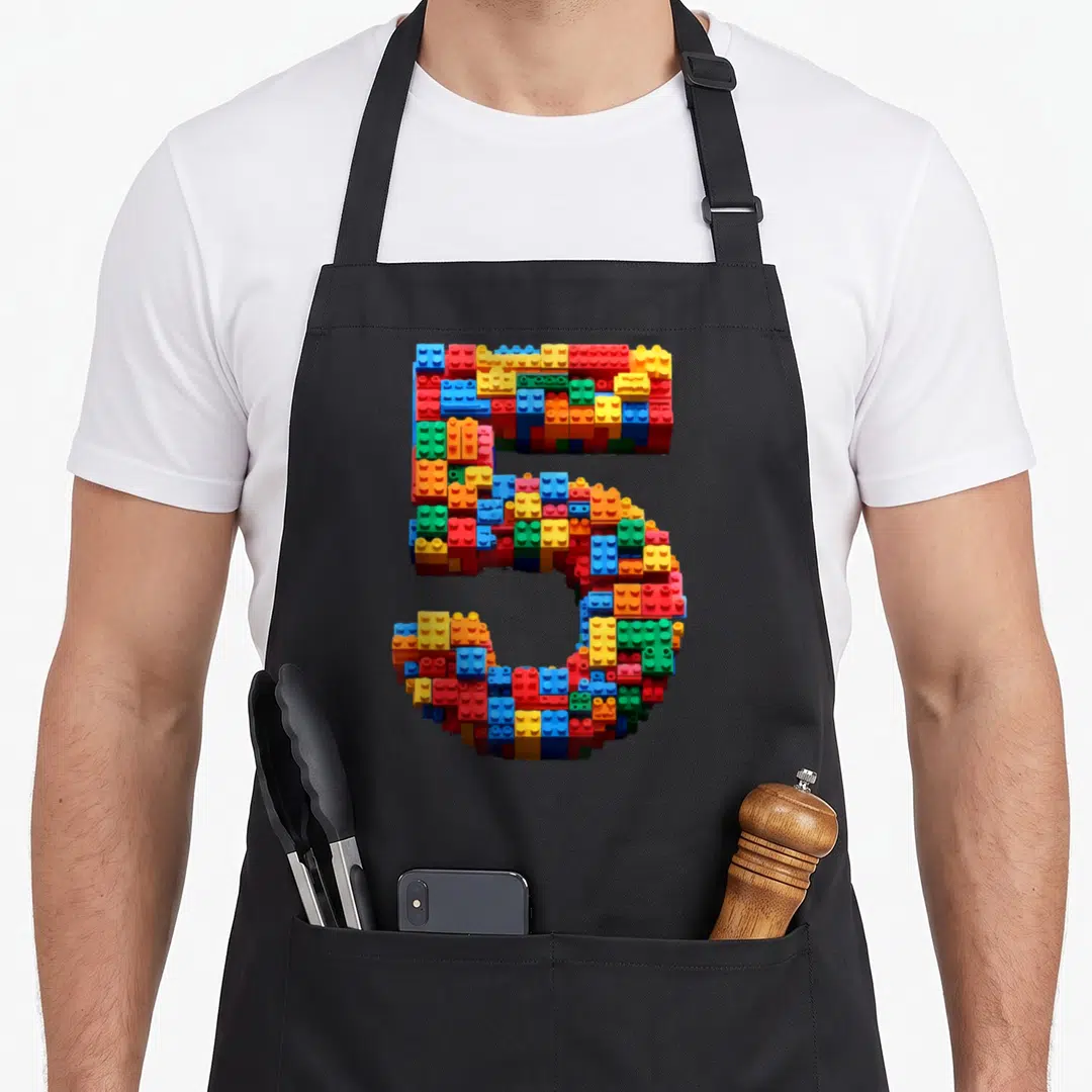 Block master building aprons - Number 5 formed by red blue yellow green and orange interlocking plastic bricks — shown on a black cotton canvas apron against a white background