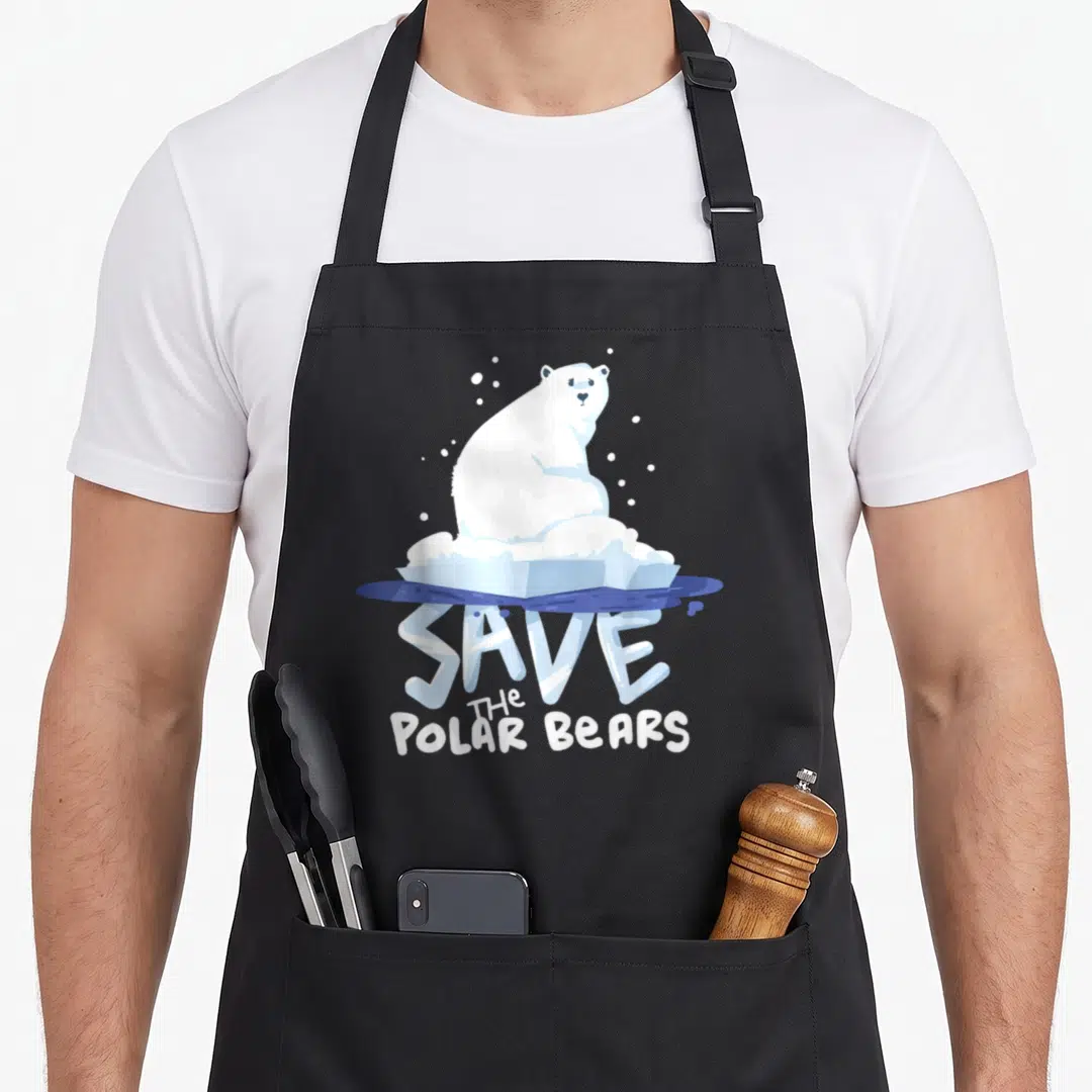 Save bear apron - Cartoon polar bear on ice floe with stacked SAVE THE POLAR BEARS text in white and blue — shown on a black cotton canvas apron against a white background