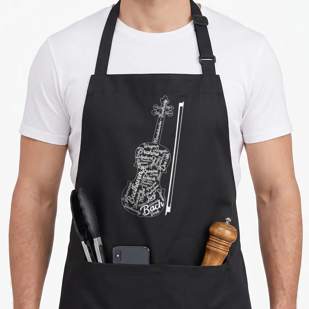 Classical violin apron - White typographic violin shape formed by composer names with a standing bow on black fabric — shown on a black cotton canvas apron against a white background