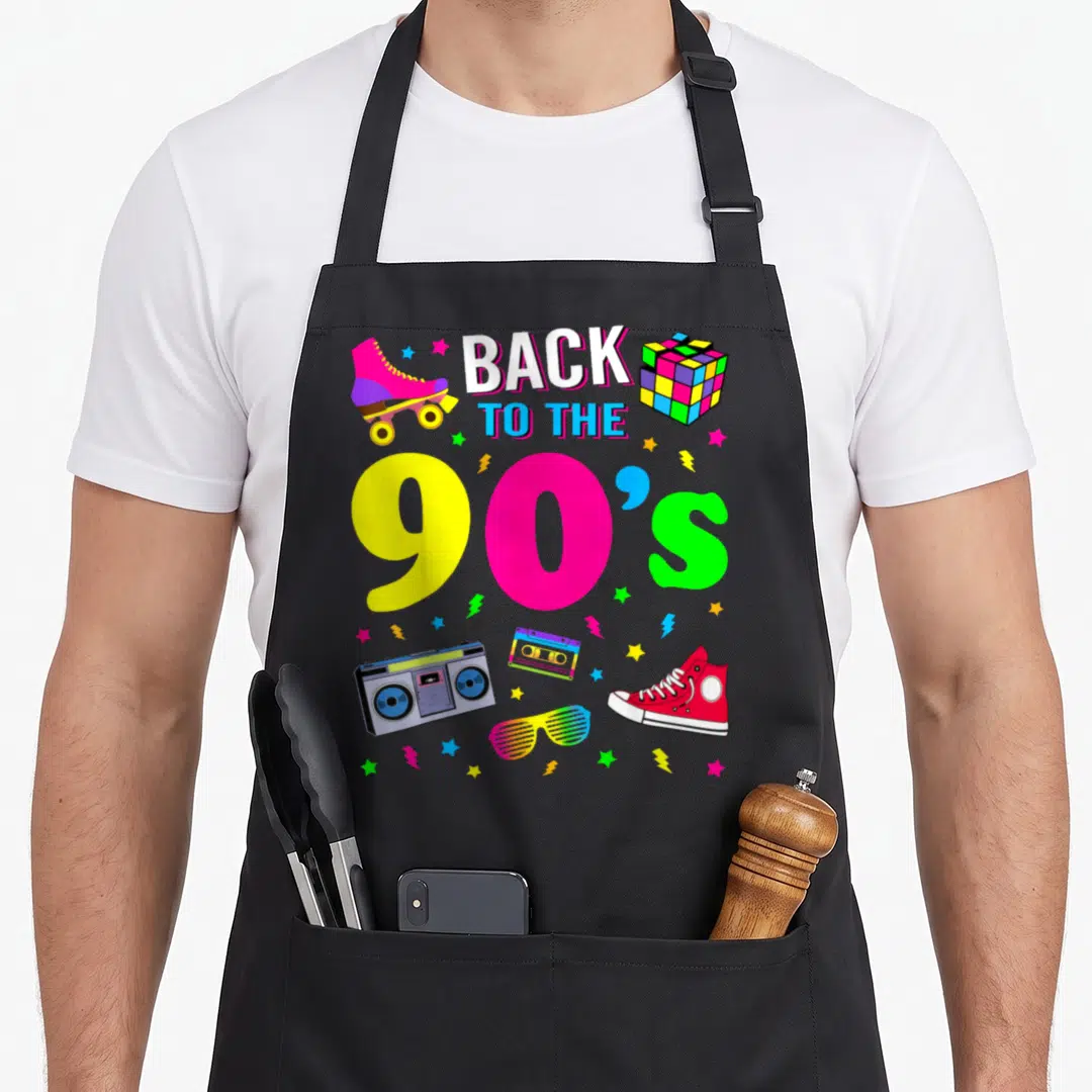 Ninety 90s apron - Back to the 90s text with boombox, roller skate, and colorful stars in cartoon style — shown on a black cotton canvas apron against a white background