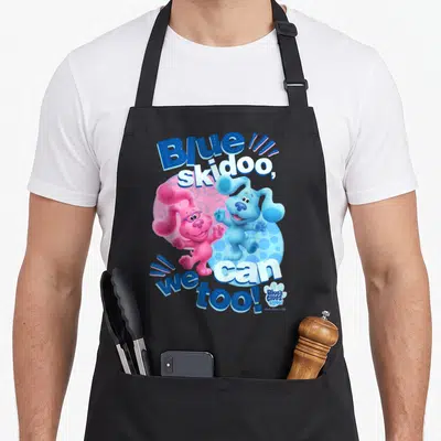 Clue blue apron - Two cartoon dogs on polka dot circle with Blue skidoo we can too text — shown on a black cotton canvas apron against a white background