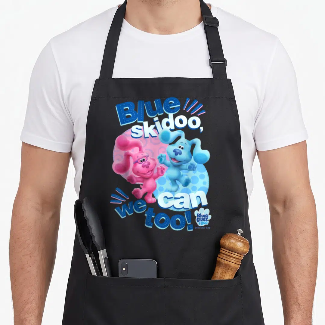 Clue blue apron - Two cartoon dogs on polka dot circle with Blue skidoo we can too text — shown on a black cotton canvas apron against a white background