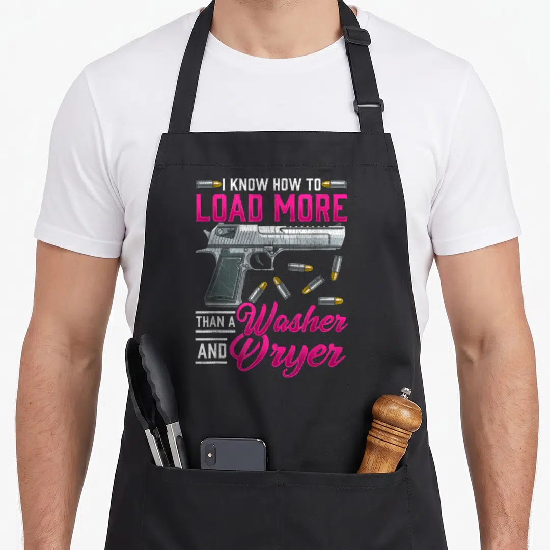 Enthusiast shooting apron - Silver handgun with pink text I KNOW HOW TO LOAD MORE THAN A Washer AND Dryer and scattered — shown on a black cotton canvas apron against a white background