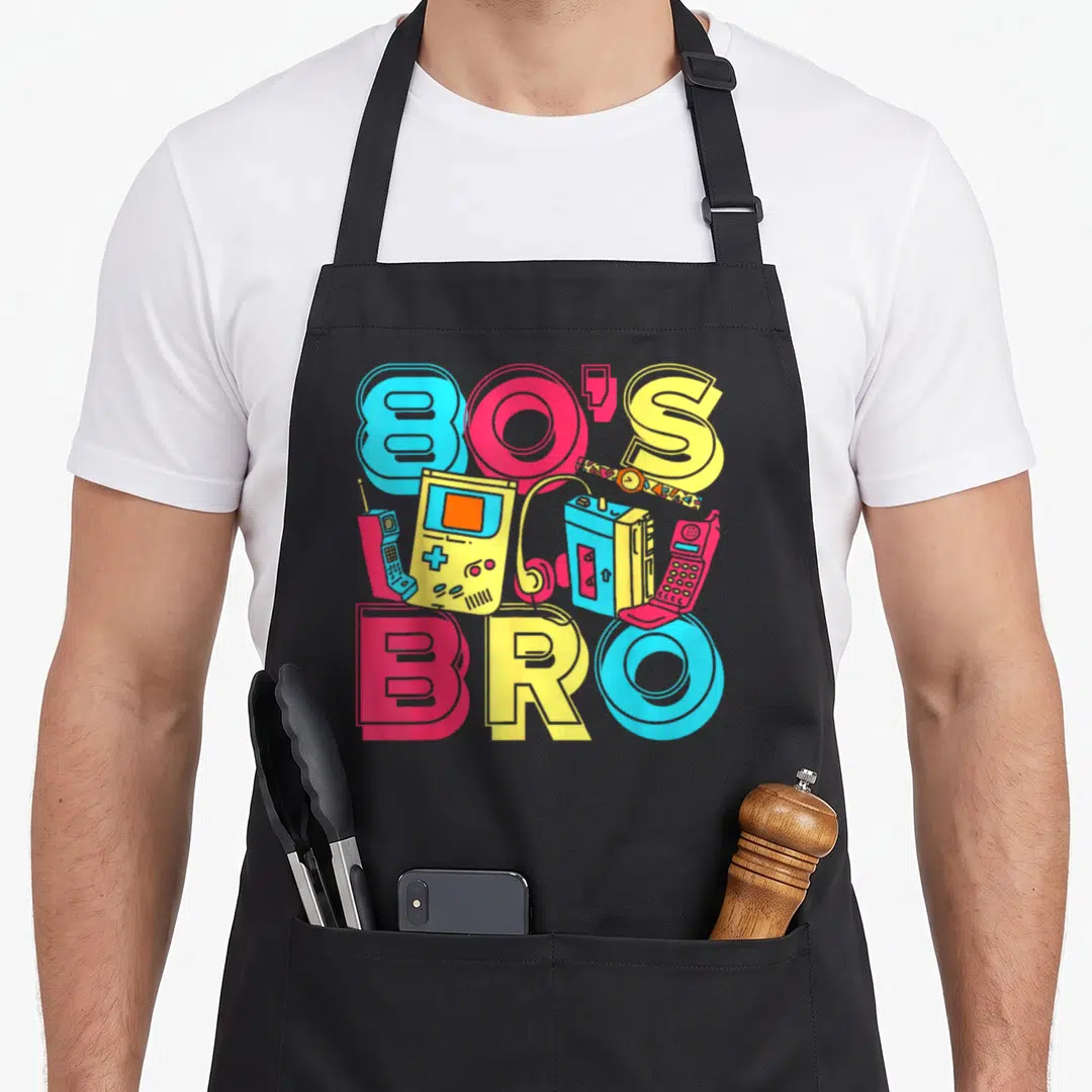 Costume 1980s apron - Cartoon 80s BRO text with blue red yellow boombox phone and game console cluster — shown on a black cotton canvas apron against a white background