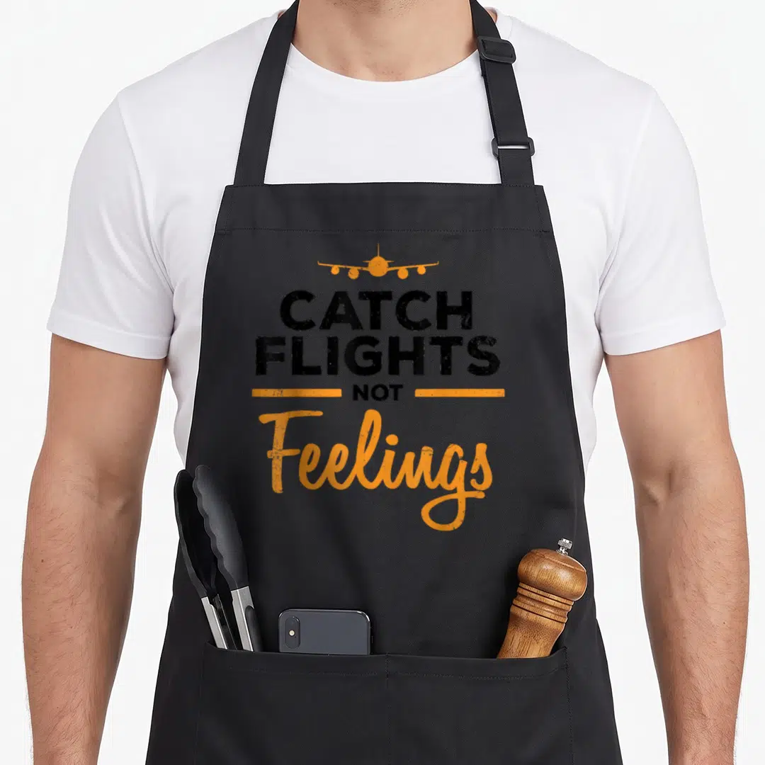 Feeling flight attendant apron - Orange plane graphic above CATCH FLIGHTS NOT Feelings text in black and orange — shown on a black cotton canvas apron against a white background