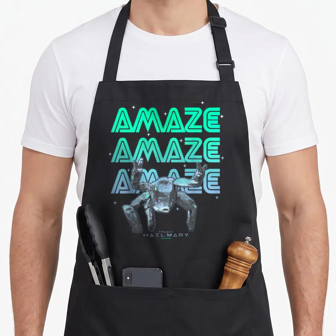 Project amazing aprons - Stacked AMAZE text with grey alien creature and small stars — shown on a black cotton canvas apron against a white background