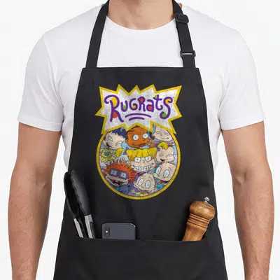 Baby circle time apron - Rugrats logo in jagged burst above circle of cartoon baby faces in yellow purple blue orange — shown on a black cotton canvas apron against a white background