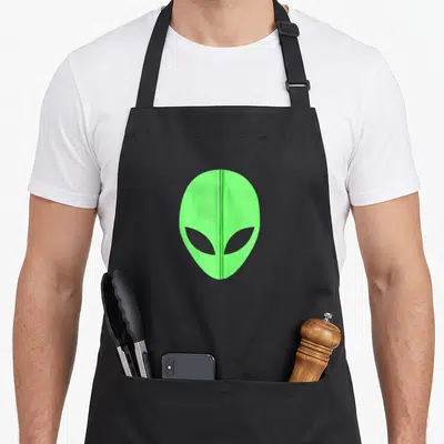 Ufo zip apron - Lime green alien head with vertical zipper running down the center — shown on a black cotton canvas apron against a white background