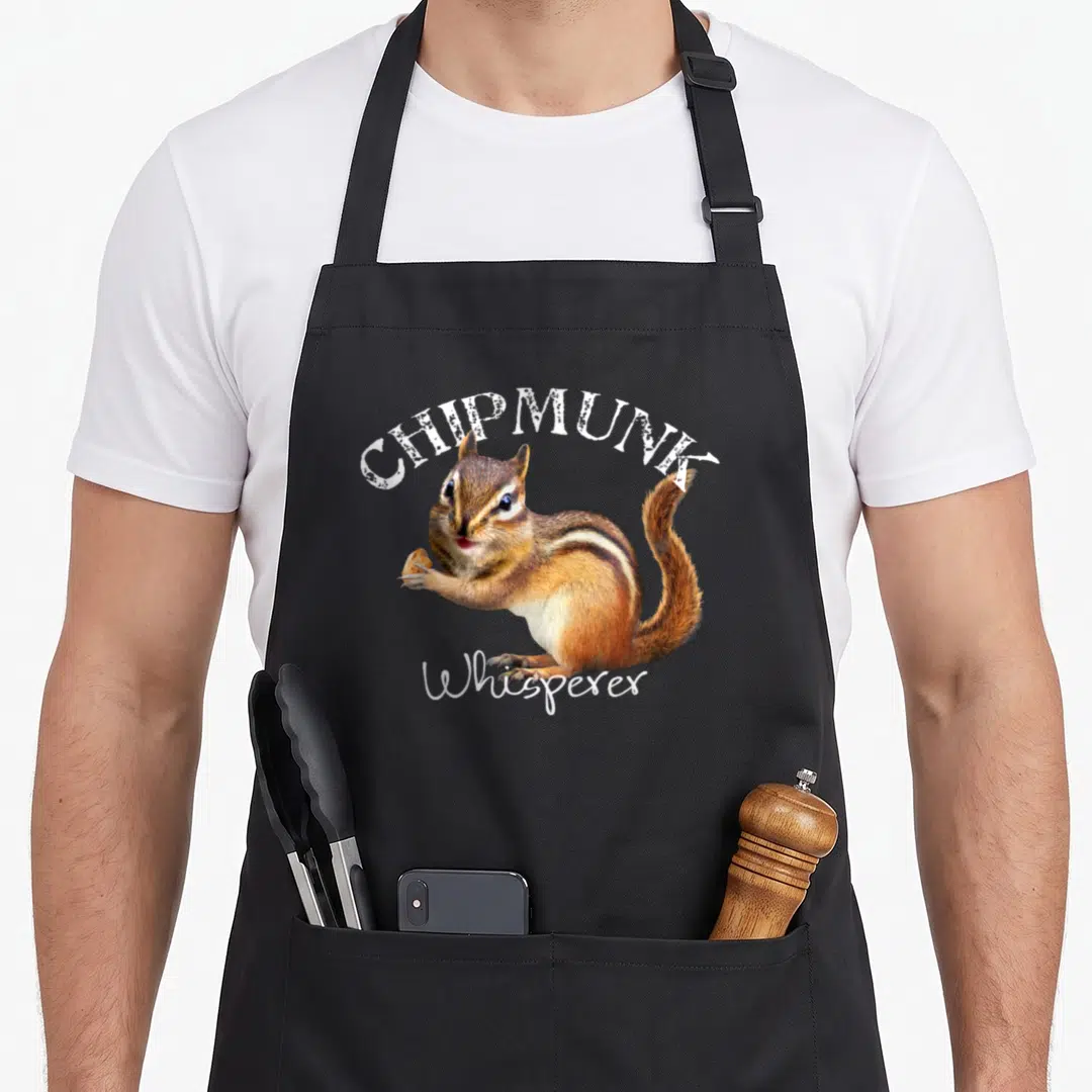 Whisperer chipmunk apron - Realistic chipmunk holding a nut with CHIPMUNK Whisperer text in brown and white — shown on a black cotton canvas apron against a white background