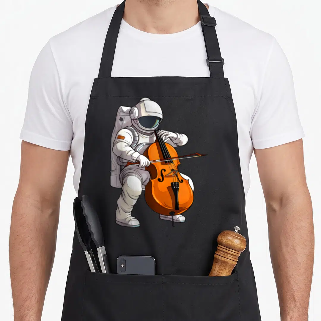 Astronaut cello apron - Cartoon astronaut in white suit playing large orange cello with bow on grey background — shown on a black cotton canvas apron against a white background