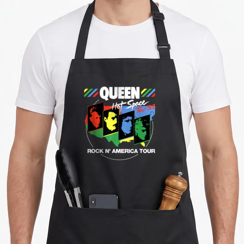 Hot queen apron - QUEEN Hot Space Tour 82 band profiles in colored rectangles over USA map — shown on a black cotton canvas apron against a white background