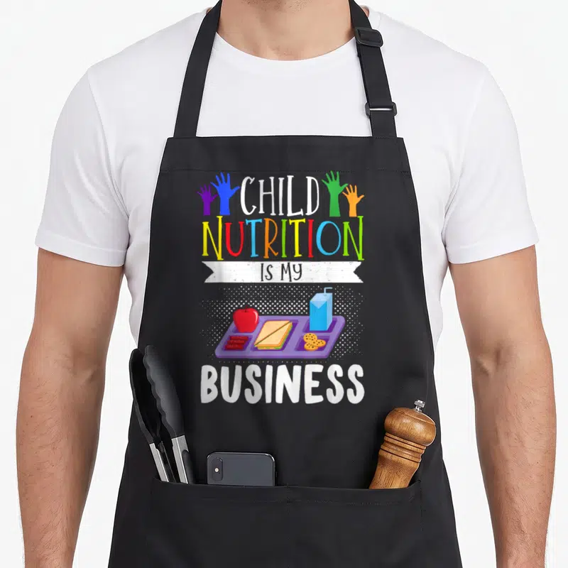 Nutrition cafeteria aprons - Purple lunch tray with red apple blue juice box and stacked text CHILD NUTRITION IS MY — shown on a black cotton canvas apron against a white background