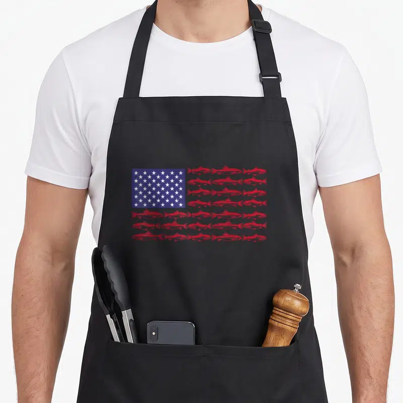 Largemouth american flag apron - Red fish arranged in rows forming stripes next to a blue rectangle with white stars — shown on a black cotton canvas apron against a white background