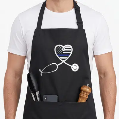 Police nurse apron - White stethoscope outlines heart filled with distressed flag and blue line — shown on a black cotton canvas apron against a white background