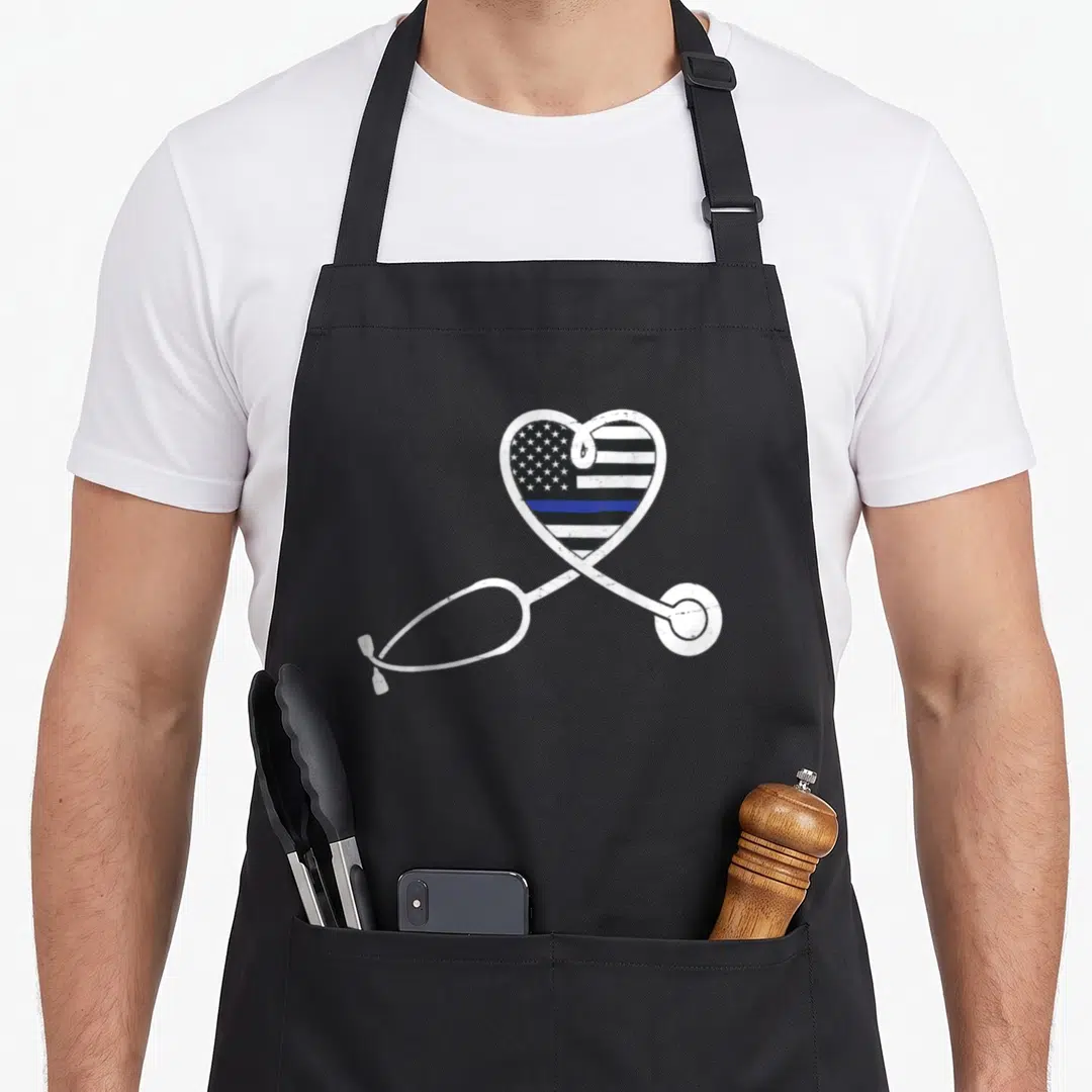 Police nurse apron - White stethoscope outlines heart filled with distressed flag and blue line — shown on a black cotton canvas apron against a white background