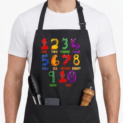 Learning math teacher apron - Red yellow green blue purple monster numbers one to ten grid — shown on a black cotton canvas apron against a white background