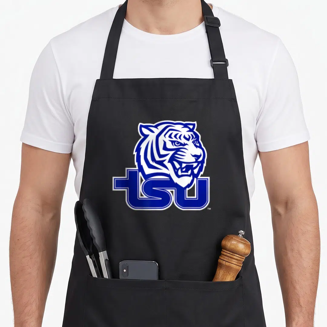 Tennessee state university apron - Blue and white cartoon tiger head above bold TSU letters — shown on a black cotton canvas apron against a white background
