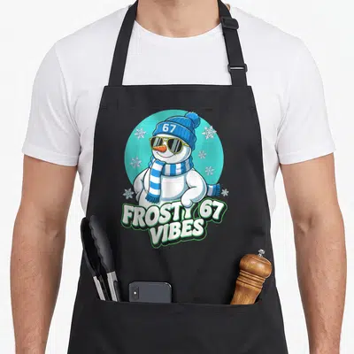 Frosty meme apron - Cartoon snowman in teal circle with FROSTY 67 VIBES text and green outline — shown on a black cotton canvas apron against a white background