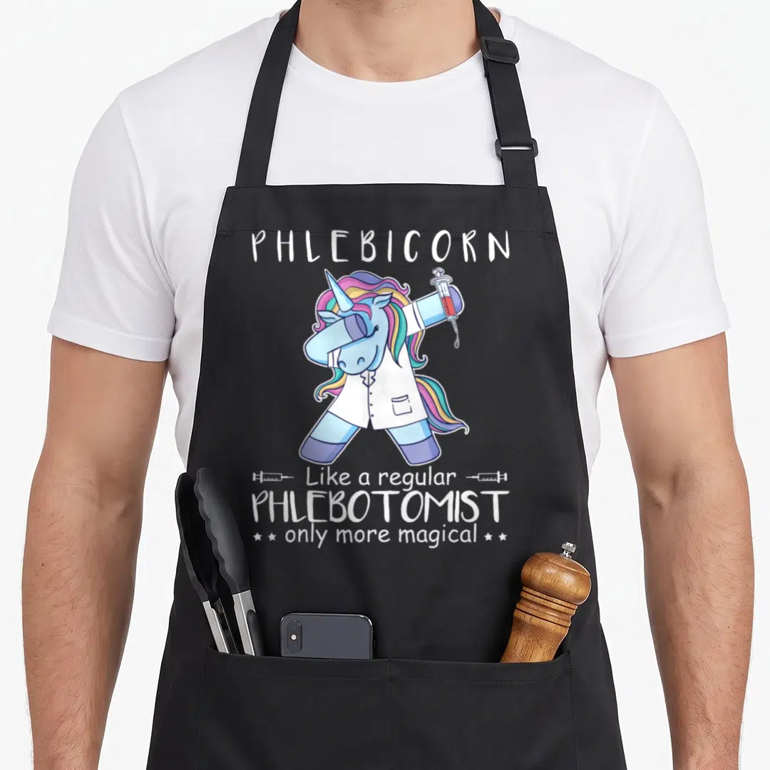 Funny phlebotomy phlebotomist apron - Dabbing blue unicorn holding syringe with PHLEBICORN text and stars — shown on a black cotton canvas apron against a white background