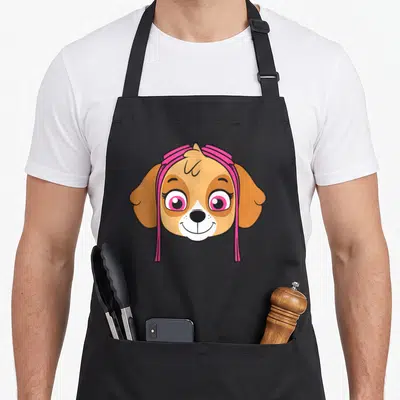 Skye face apron - Cartoon tan dog head with two pink bows and long ribbons hanging down — shown on a black cotton canvas apron against a white background