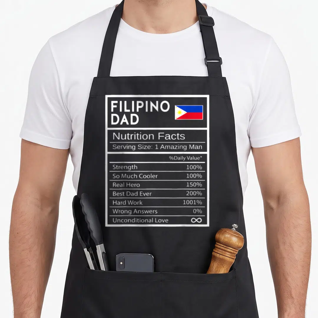Fact pride apron - Nutrition facts label design listing Filipino Dad traits including 1001% hard work and infinite — shown on a black cotton canvas apron against a white background