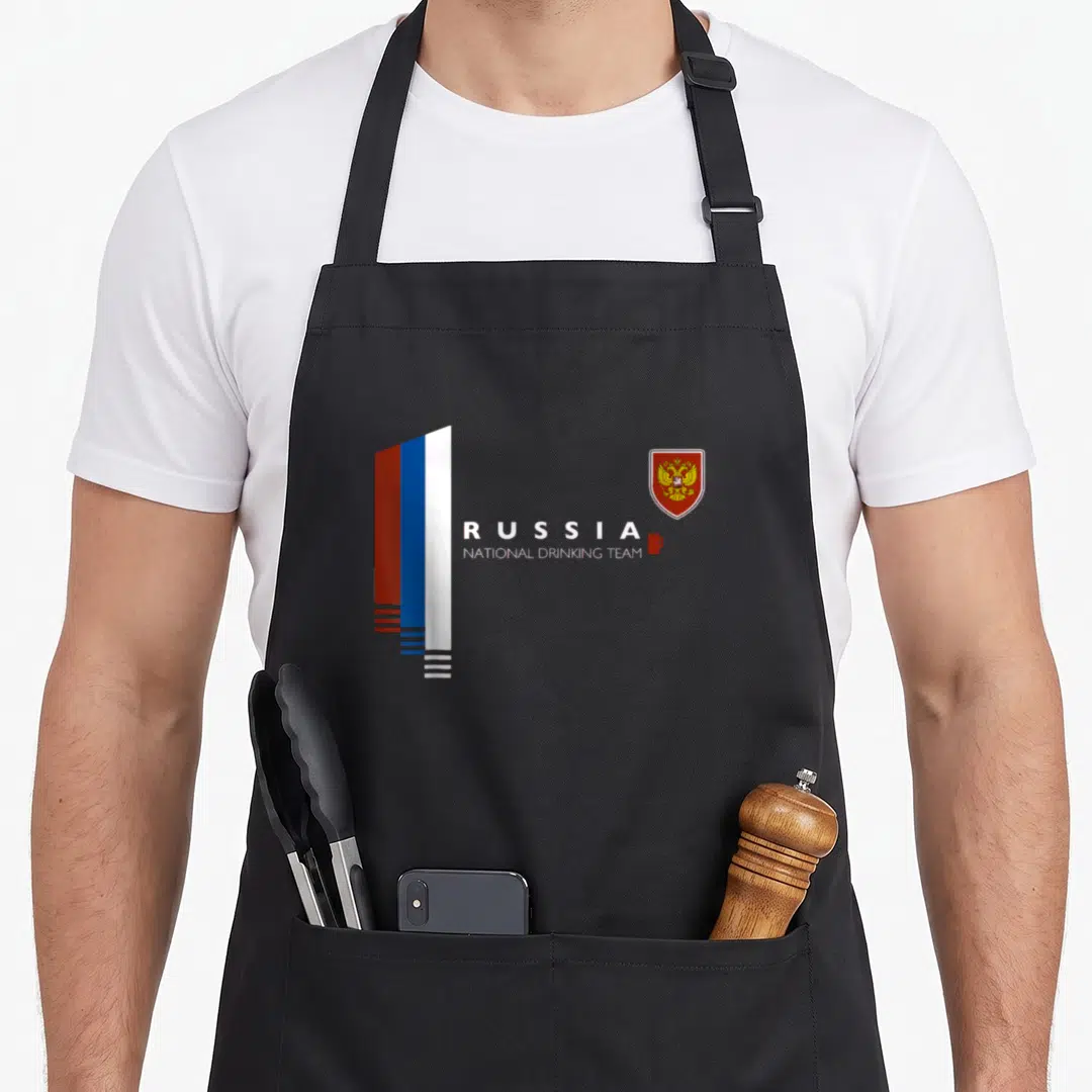 National russian apron - Russia flag stripes, drinking team text, mug, and coat of arms — shown on a black cotton canvas apron against a white background