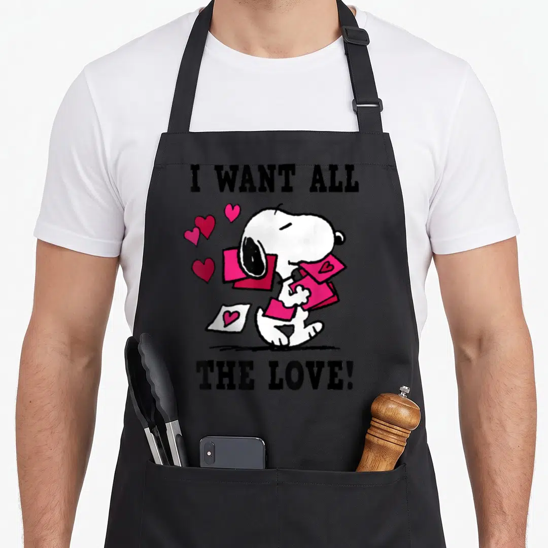Cool valentine apron - Snoopy holding pink envelopes with hearts and text I WANT ALL THE LOVE — shown on a black cotton canvas apron against a white background