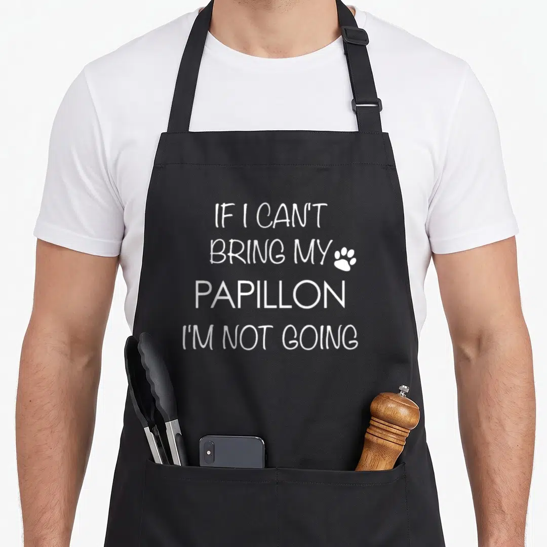 Papillion dog apron - White stacked text IF I CAN'T BRING MY PAPILLON I'M NOT GOING with paw print icon — shown on a black cotton canvas apron against a white background