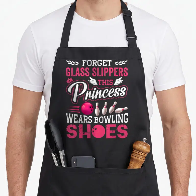 Bowling wife apron - Pink and white text reading forget glass slippers this princess wears bowling shoes with ball — shown on a black cotton canvas apron against a white background