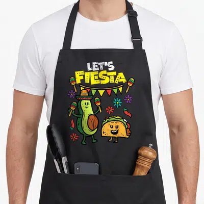 Taco avocado mexican apron - Cartoon avocado wearing a sombrero holding maracas next to a smiling taco under LET'S — shown on a black cotton canvas apron against a white background
