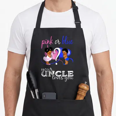 Uncle apron or apron - Two cartoon babies flank a white question mark under pink and blue text on a black apron — shown on a black cotton canvas apron against a white background
