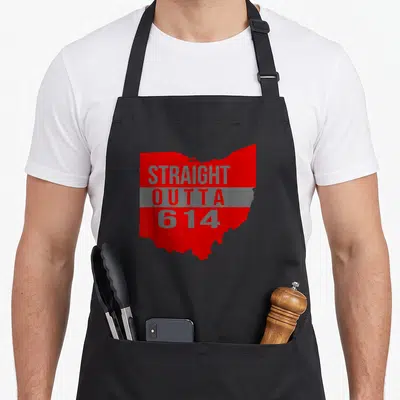 Straight columbus apron - Red Ohio state silhouette with stacked grey STRAIGHT OUTTA 614 text over a grey horizontal — shown on a black cotton canvas apron against a white background
