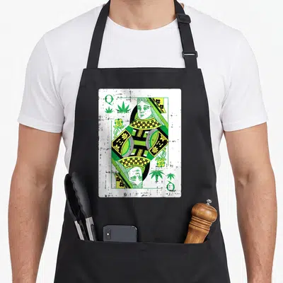 Queen smoker apron - Distressed queen of hearts playing card with green cannabis leaves and Q in corners — shown on a black cotton canvas apron against a white background