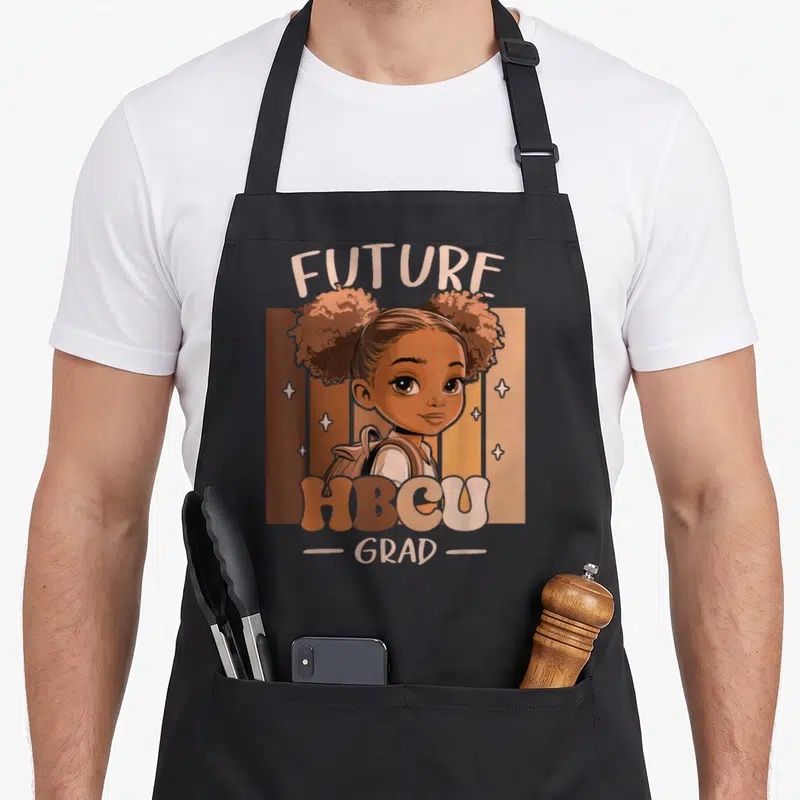 Grad motivational grade apron - Cartoon girl with afro puffs and backpack amid brown tan peach stripes with FUTURE HBCU — shown on a black cotton canvas apron against a white background