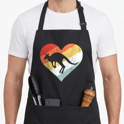 80s gday kangaroo apron - Grey kangaroo silhouette inside a heart with red orange yellow white and light blue stripes — shown on a black cotton canvas apron against a white background