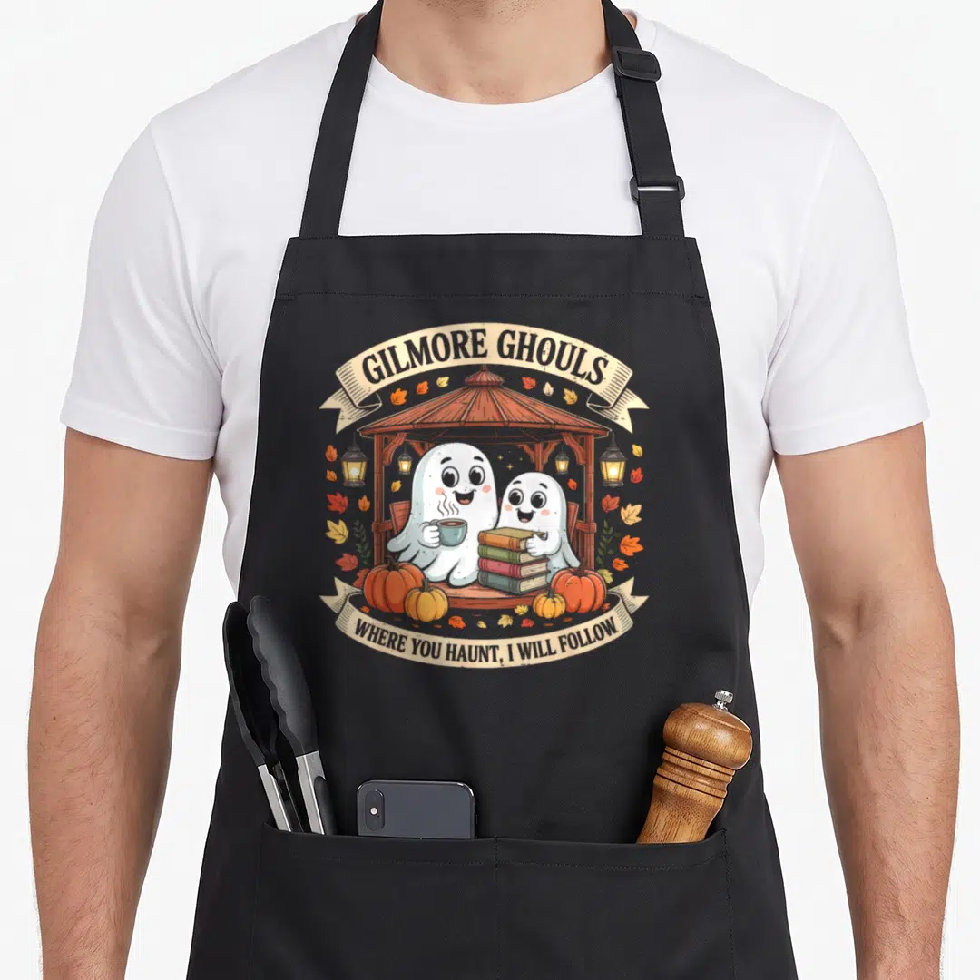 Gilmore halloween apron - Two white ghosts in a gazebo holding books and coffee with orange pumpkins and arched text — shown on a black cotton canvas apron against a white background