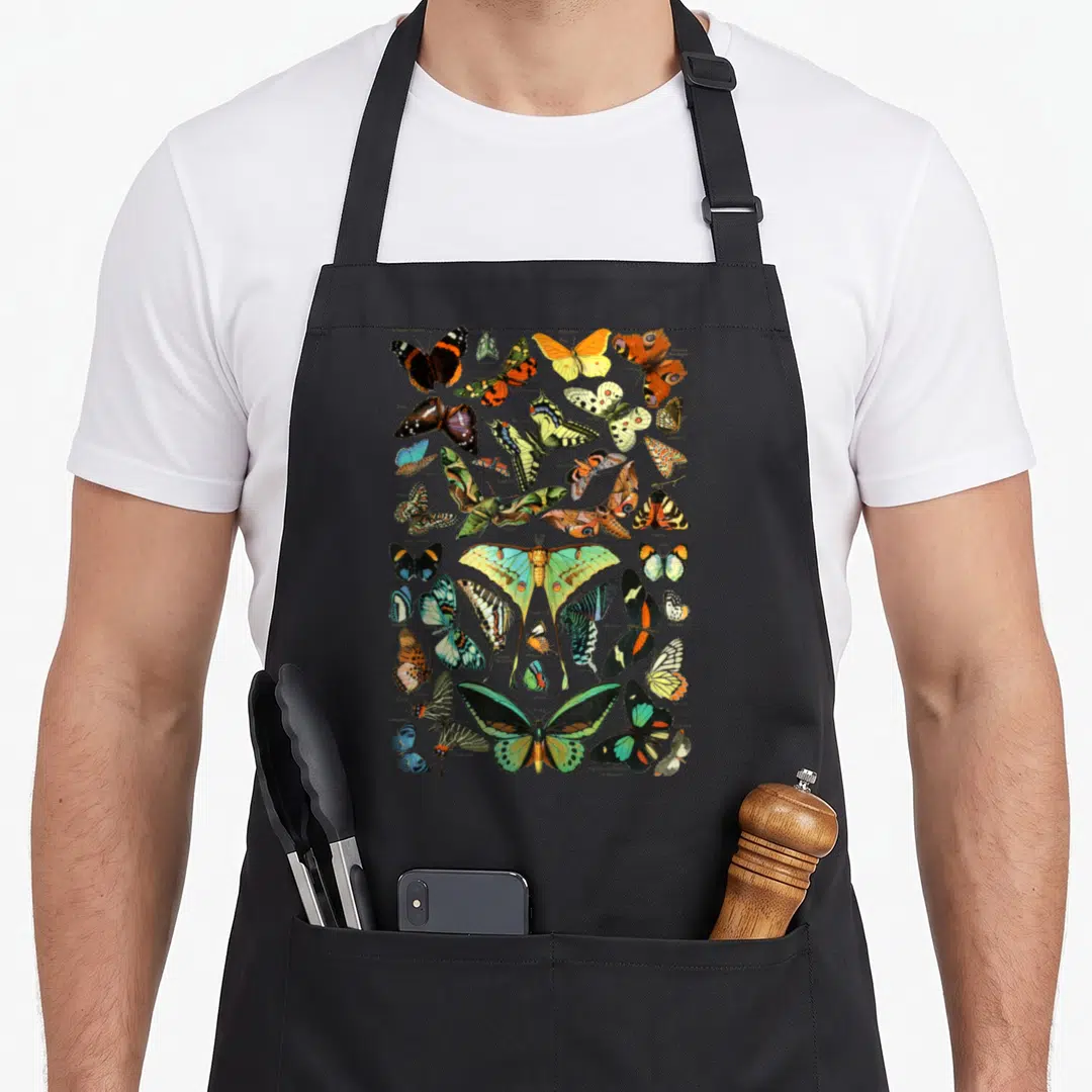 Specy butterfly apron - Vintage collection of butterflies and moths with scientific labels in orange, yellow, green — shown on a black cotton canvas apron against a white background