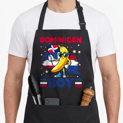 Republic dominican boy apron - Cartoon banana holding flag with DOMINICAN BOY text and stars — shown on a black cotton canvas apron against a white background