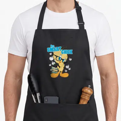 Chick smart apron - Tweety Bird wearing glasses holding books with apple on top and One SMART CHICK text — shown on a black cotton canvas apron against a white background