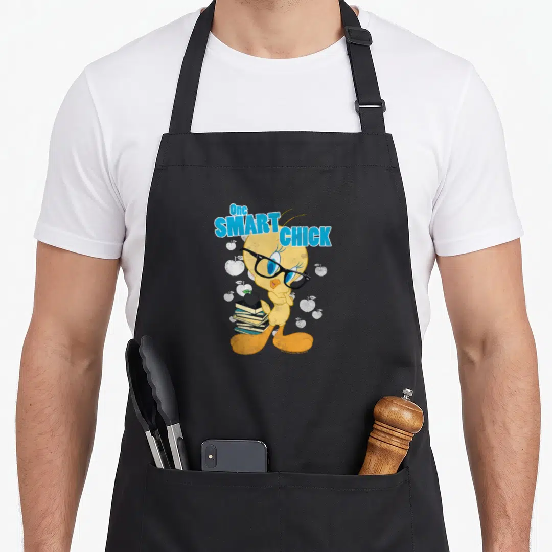 Chick smart apron - Tweety Bird wearing glasses holding books with apple on top and One SMART CHICK text — shown on a black cotton canvas apron against a white background